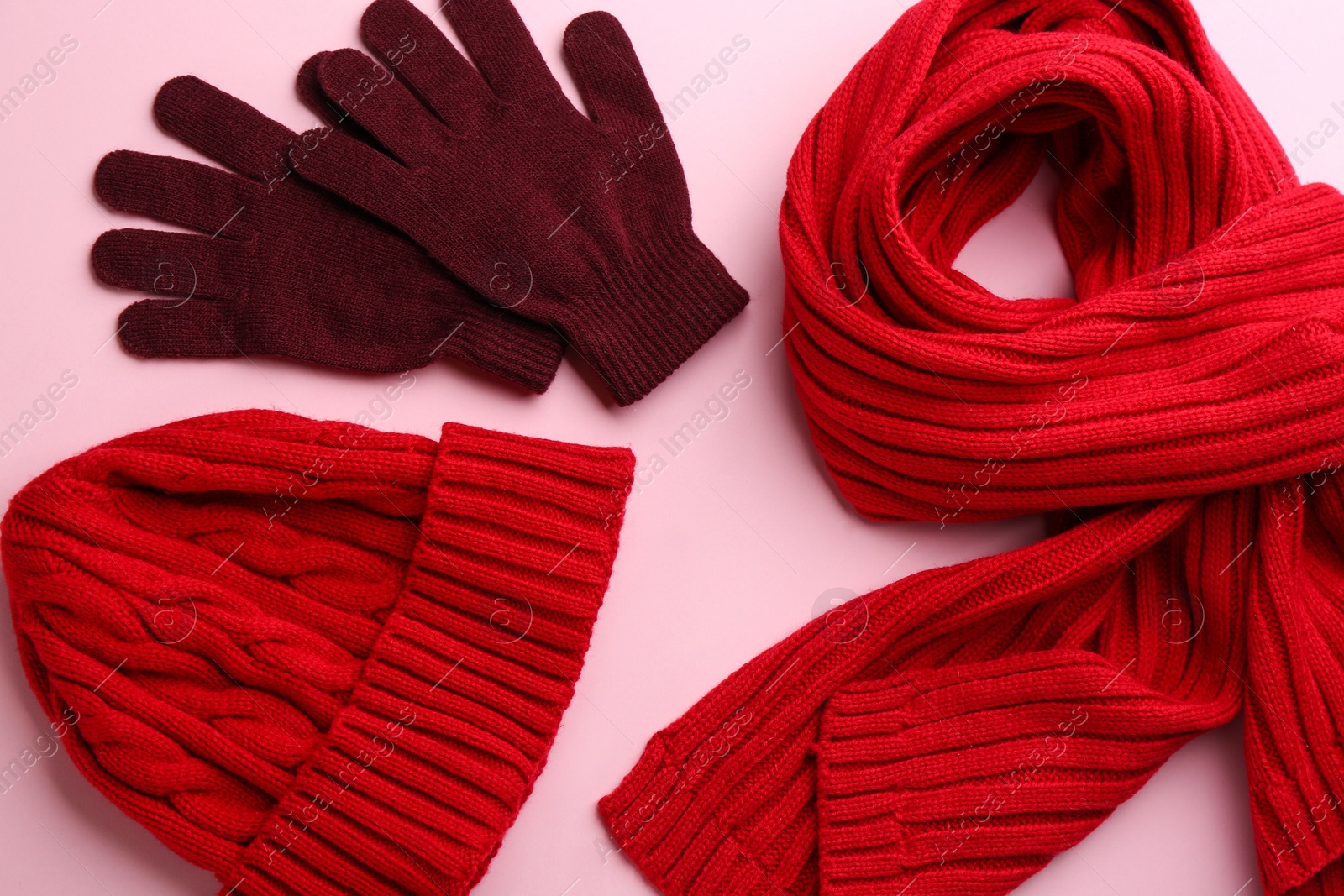 Photo of Stylish gloves, scarf and hat on pink background, flat lay