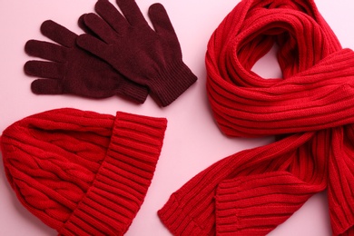 Stylish gloves, scarf and hat on pink background, flat lay