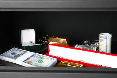 Photo of Open steel safe with money and jewelry