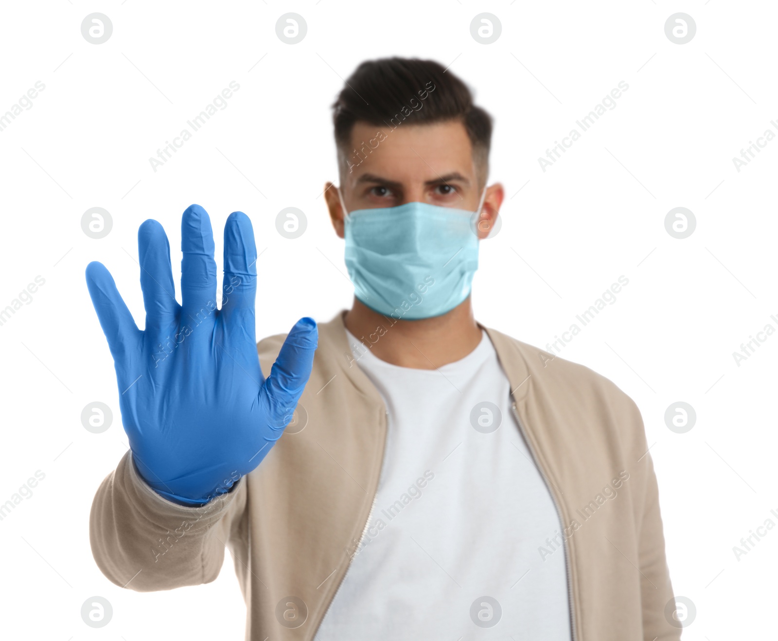 Photo of Man in protective face mask and medical gloves showing stop gesture against white background, focus on hand