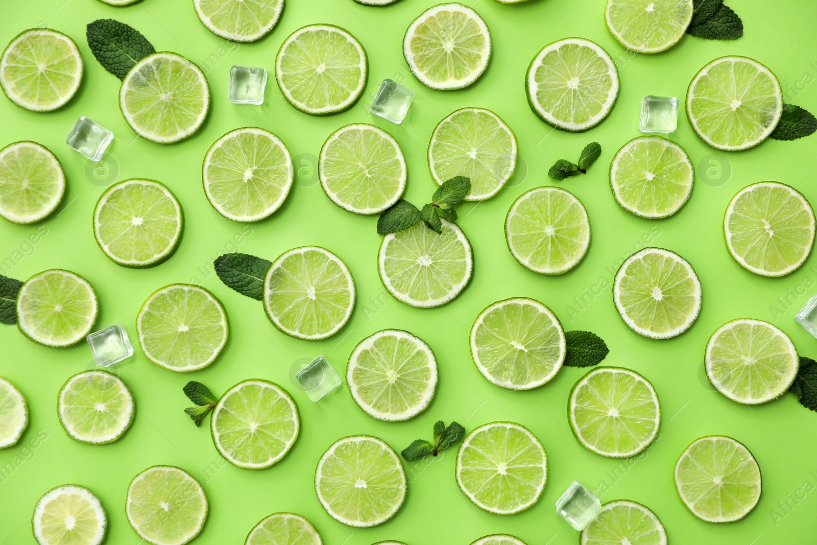 Photo of Flat lay composition with slices of fresh juicy limes on green background