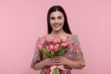 Photo of Happy young woman with beautiful bouquet on dusty pink background