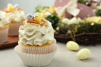 Photo of Tasty Easter cupcakes with vanilla cream and festive decor on gray table