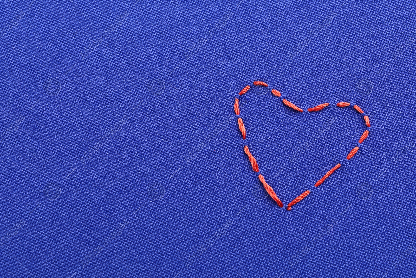 Photo of Embroidered heart on blue cloth, top view