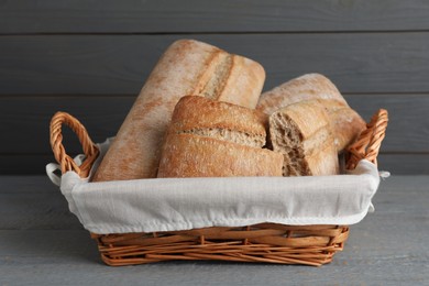 Delicious ciabattas in wicker basket on wooden table