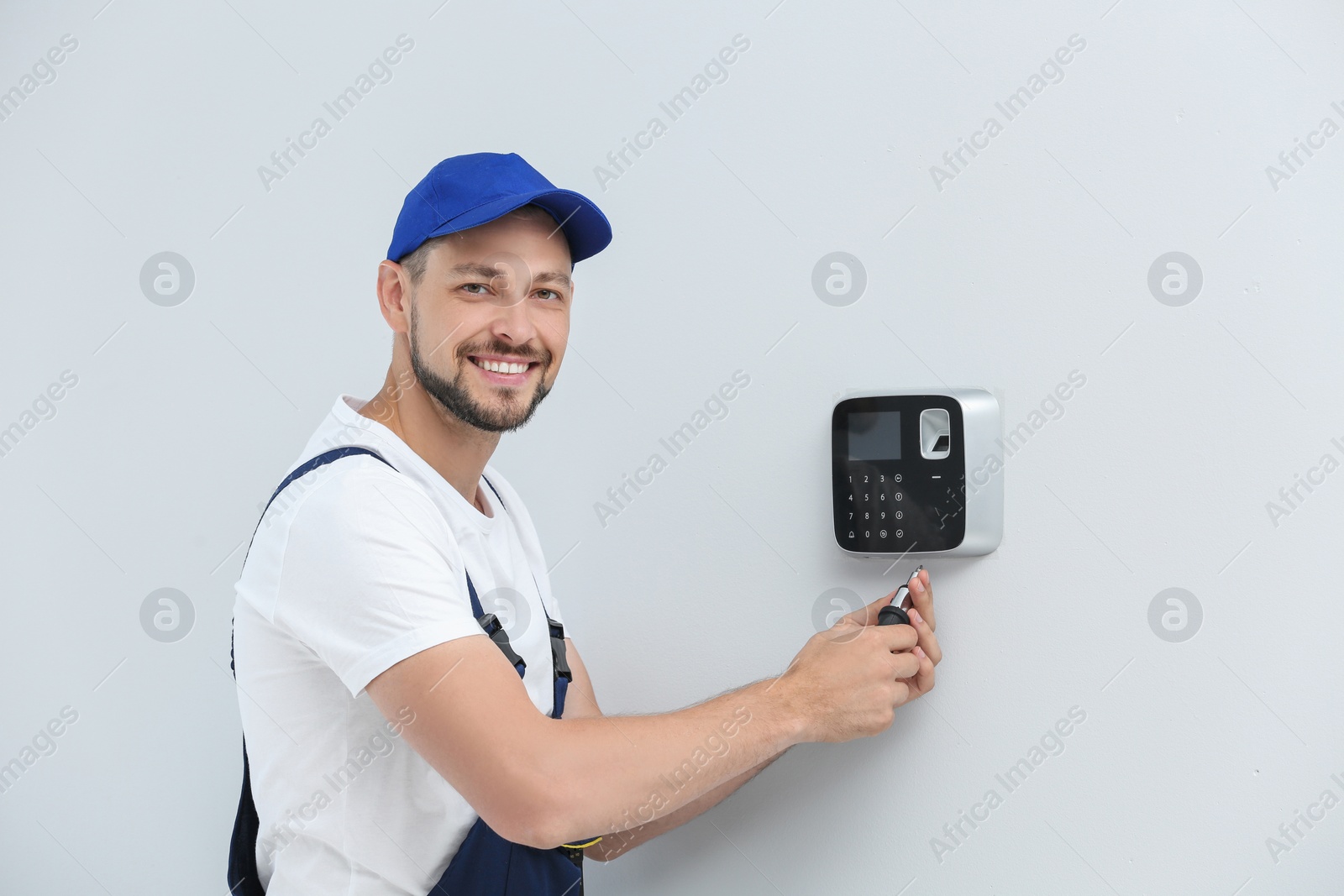 Photo of Male technician installing alarm system indoors