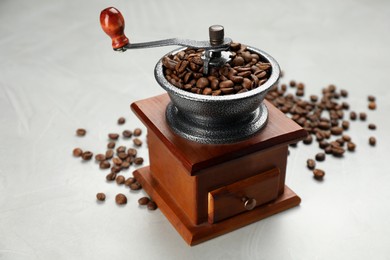 Photo of Vintage manual coffee grinder with beans on light grey table