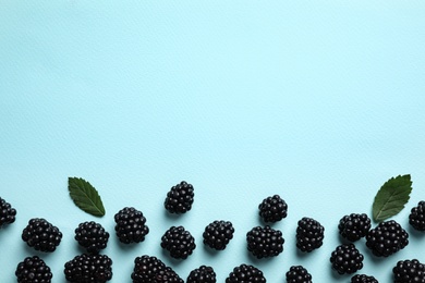Photo of Tasty ripe blackberries and leaves on light blue  background, flat lay. Space for text