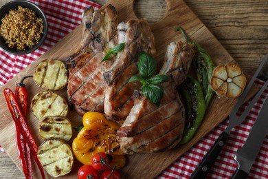 Delicious grilled meat and vegetables served on wooden table, flat lay