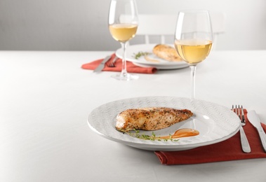 Photo of Baked lemon chicken with sauce and thyme served on white table. Space for text