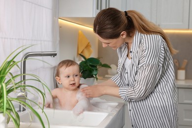 Photo of Mother washing her little baby in sink at home