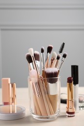 Photo of Setprofessional brushes and makeup products on wooden table indoors