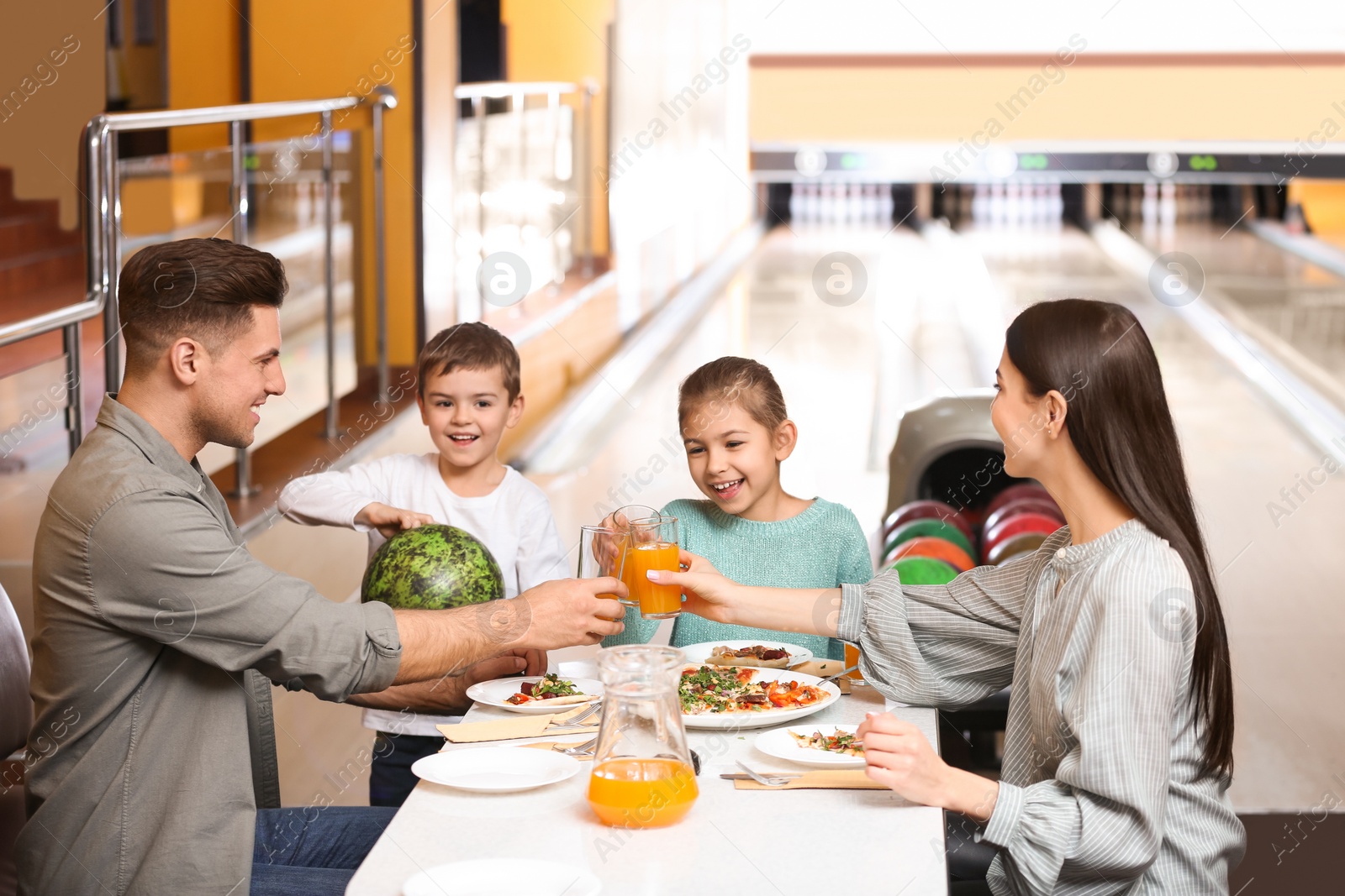 Photo of Happy family with pizza and drinks in bowling club