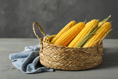Photo of Basket of corn cobs on grey wooden table