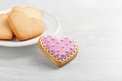 Photo of Homemade heart shaped cookies and plate on wooden table. Space for text