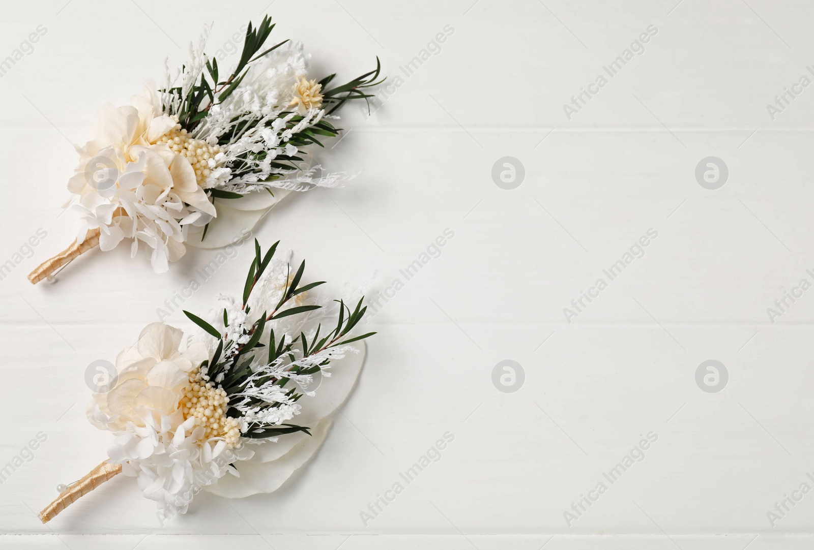 Photo of Beautiful boutonnieres on white background, flat lay. Space for text