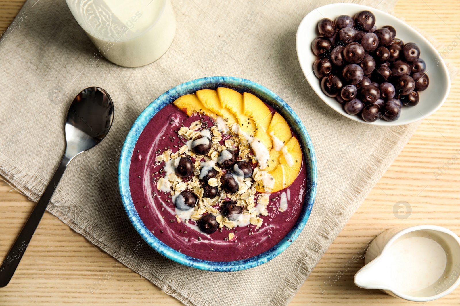 Photo of Flat lay composition with bowl of tasty acai smoothie on wooden table