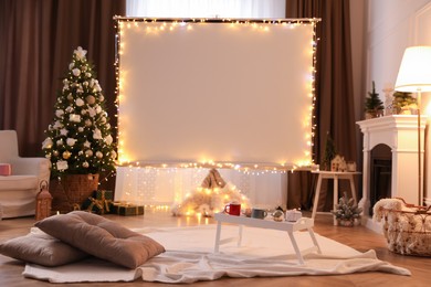 Photo of Blank video projector screen in room decorated for Christmas. Cozy atmosphere