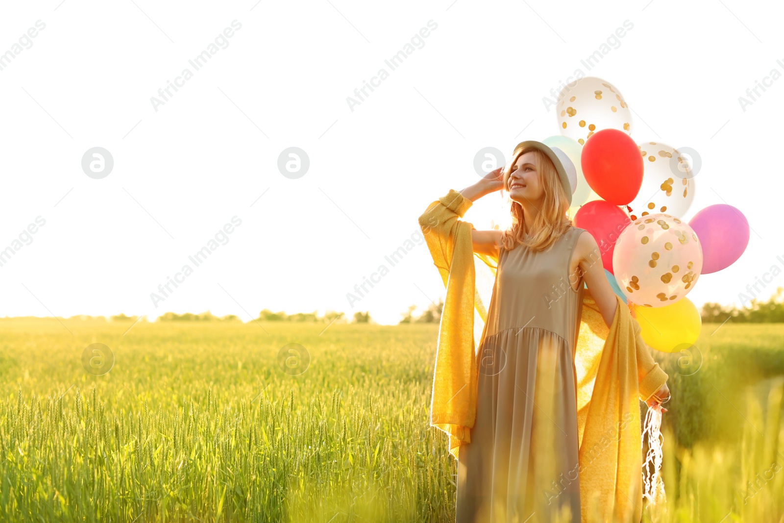 Photo of Young woman with colorful balloons outdoors on sunny day