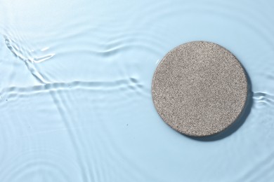 Presentation of product. Stone podium in water on light blue background, top view. Space for text