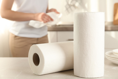 Photo of Woman wiping plate with towel in kitchen, focus on paper rolls