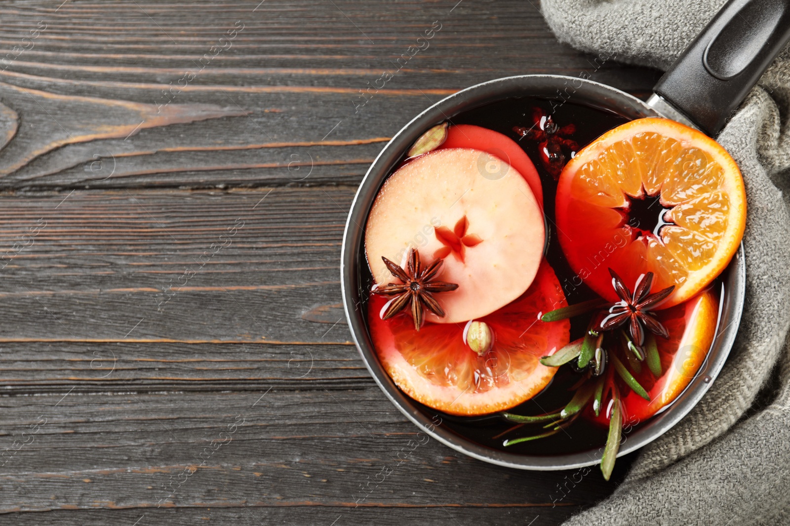 Photo of Saucepan with tasty mulled wine on black wooden table, top view. Space for text