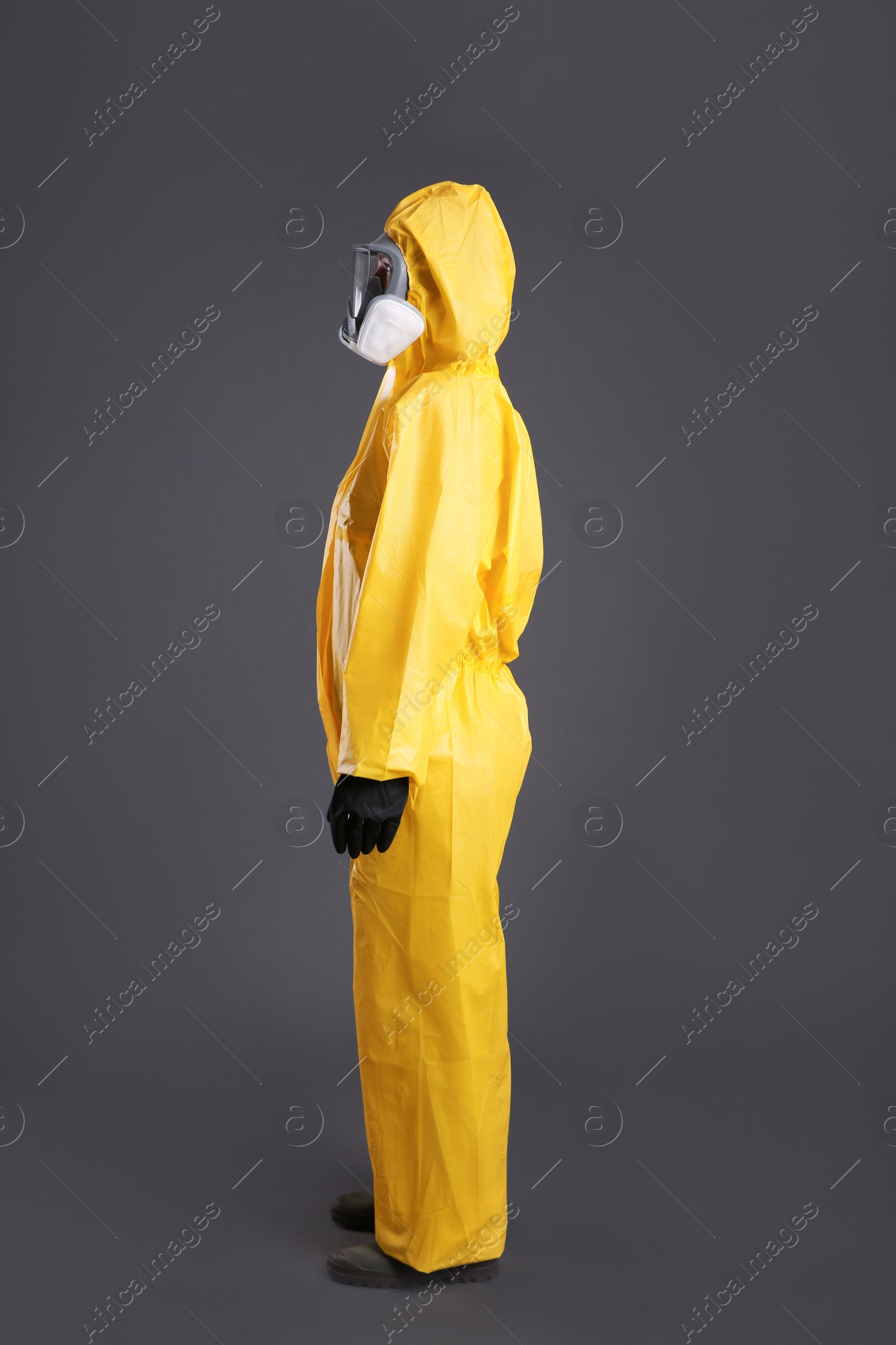 Photo of Woman wearing chemical protective suit on grey background. Virus research