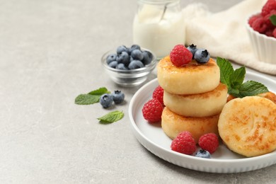 Delicious cottage cheese pancakes with berries on light table. Space for text