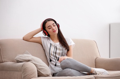 Young woman in headphones enjoying music on sofa at home