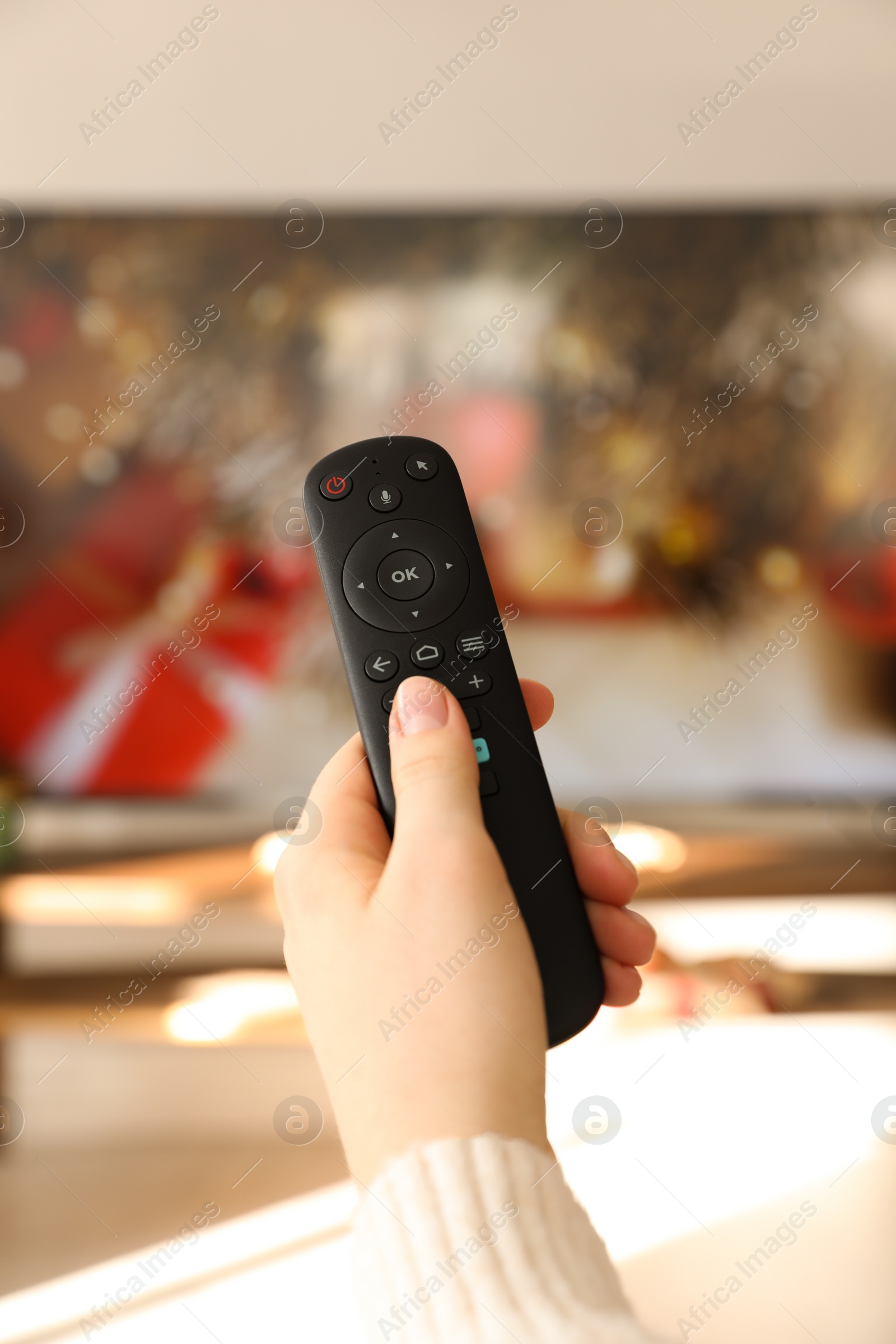 Photo of Woman with remote control watching TV at home, closeup