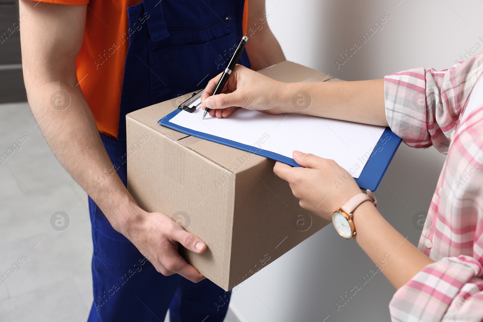 Photo of Woman receiving parcel from courier indoors, closeup