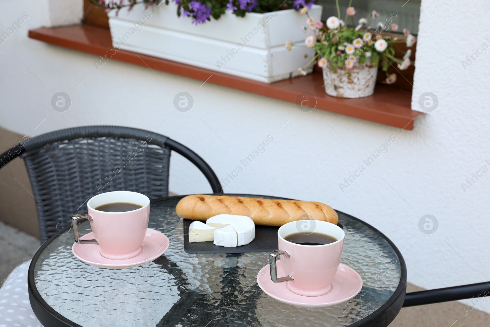 Cups of coffee, bread and cheese on glass table. Relaxing place at outdoor terrace Photo of Cups of coffee, bread and cheese on glass table. Relaxing place at outdoor terrace