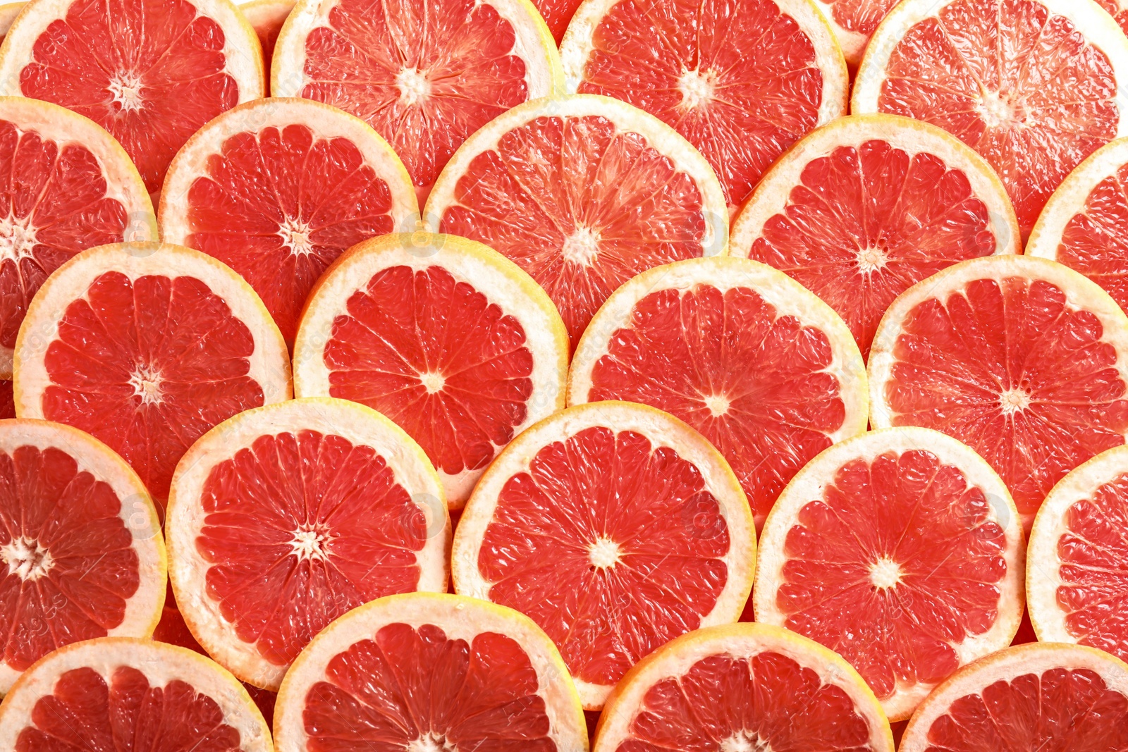 Photo of Many sliced fresh grapefruits as background, top view