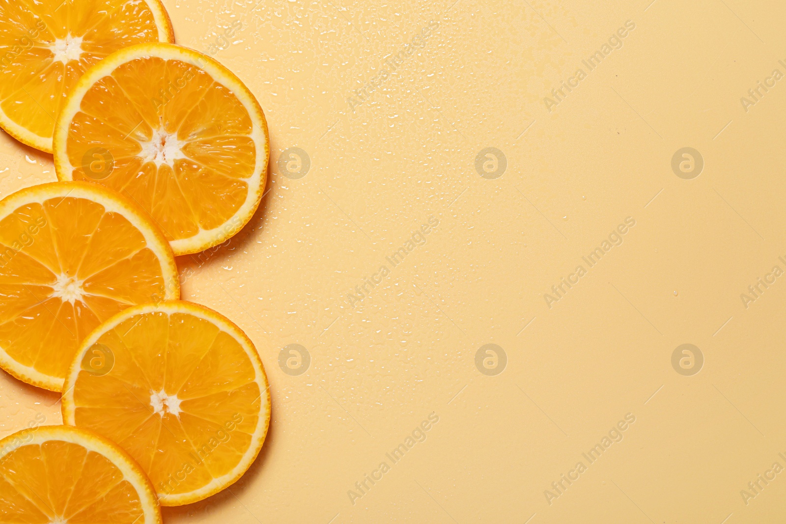 Photo of Slices of juicy orange and water on beige background, flat lay. Space for text