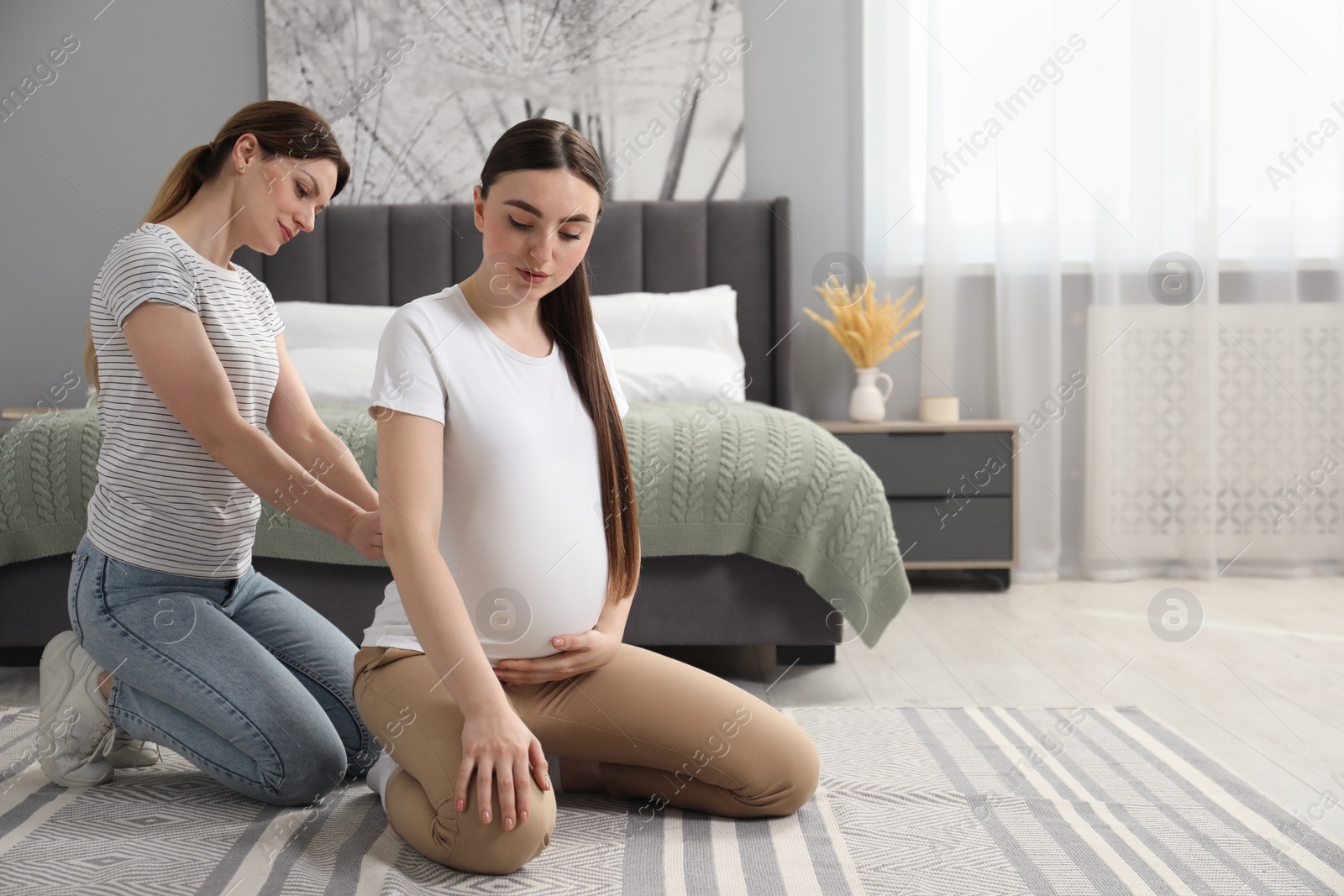 Photo of Doula massaging pregnant woman in bedroom. Preparation for child birth