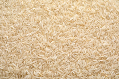 Photo of Pile of uncooked rice as background, top view