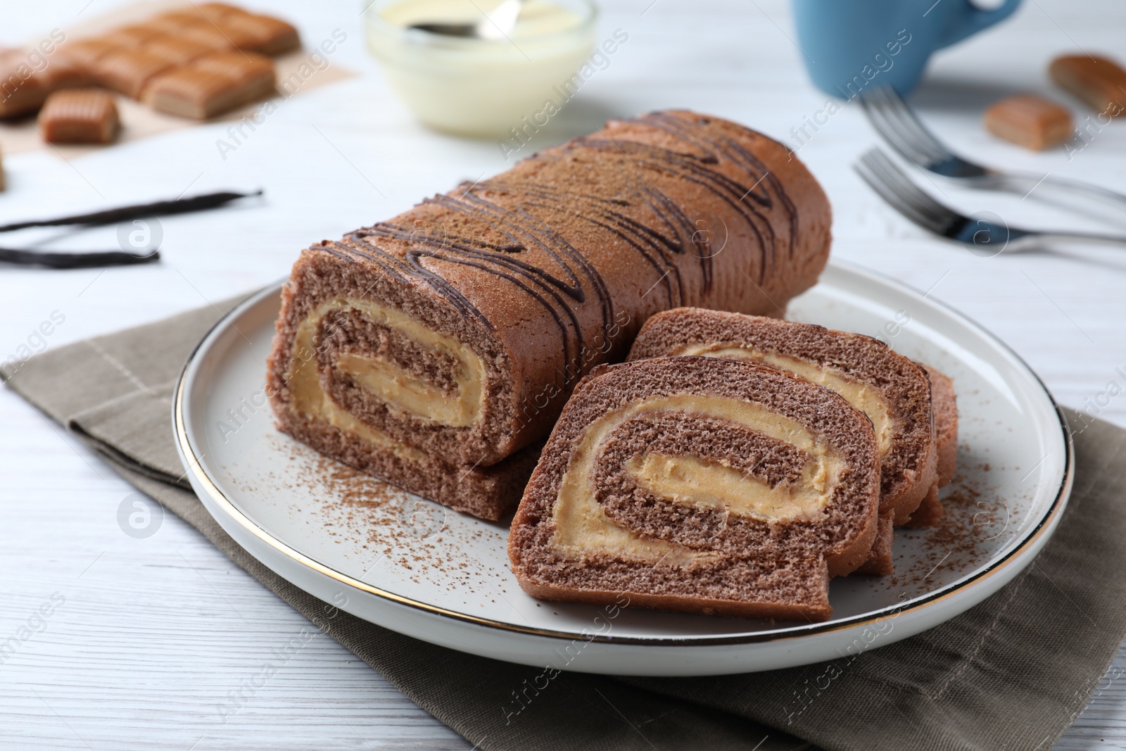 Photo of Tasty chocolate cake roll with cream on white wooden table, closeup