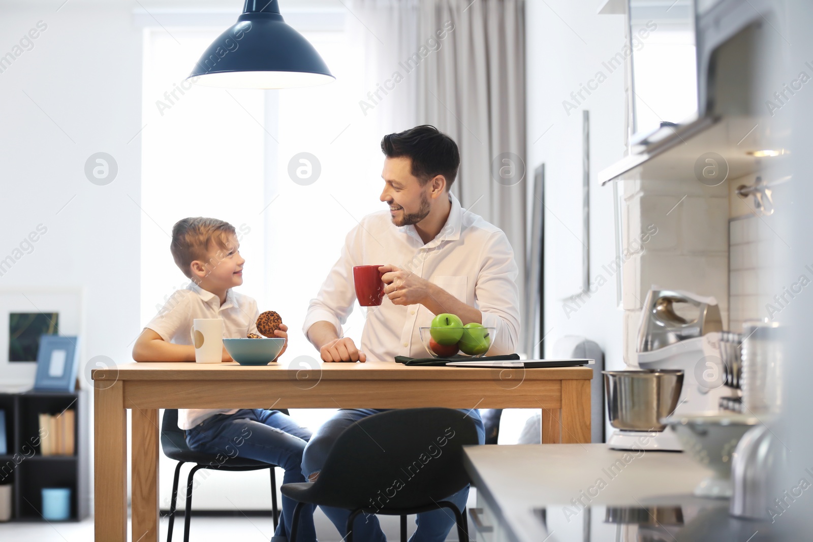 Photo of Little boy and his dad having breakfast at home