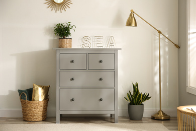 Grey chest of drawers in stylish room interior