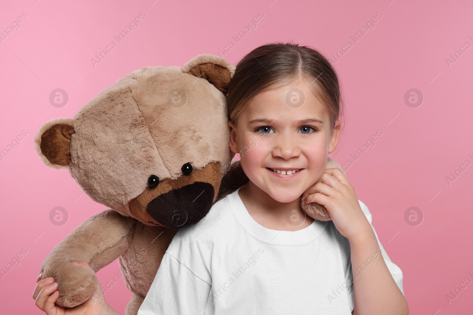 Photo of Cute girl with teddy bear on pink background