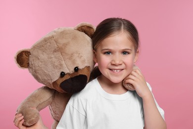 Cute girl with teddy bear on pink background