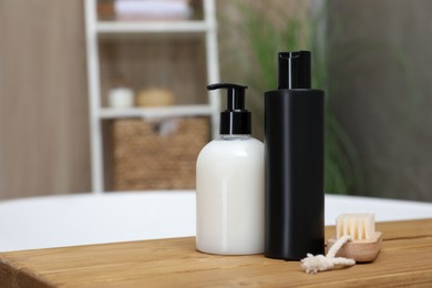 Bottles of shower gels and brush on wooden table in bathroom, space for text