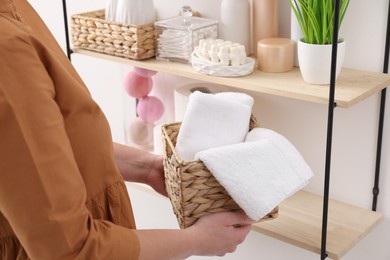 Photo of Bath accessories. Woman with basket of clean towels indoors, closeup