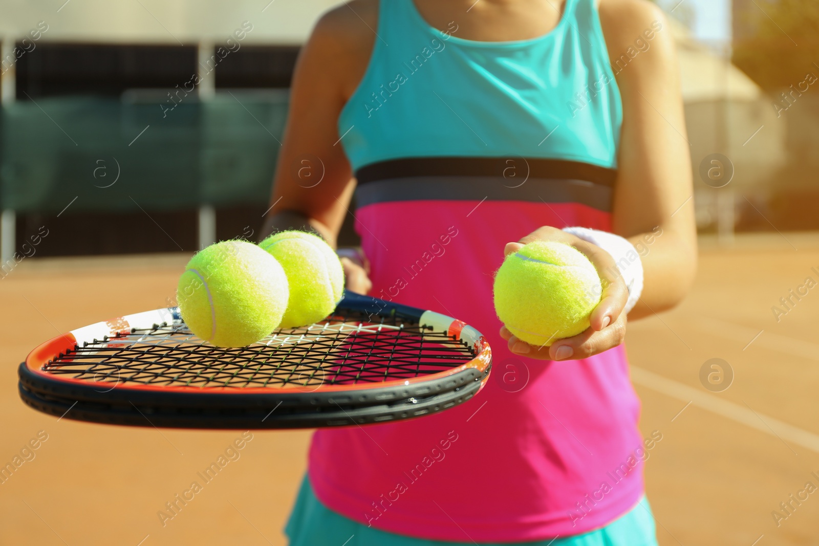 Photo of Sportswoman with racket and tennis balls at court, closeup