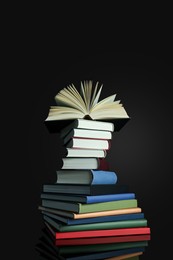 Stack of different hardcover books on black background