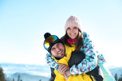 Photo of Happy couple spending time on snowy hill in mountains. Winter vacation