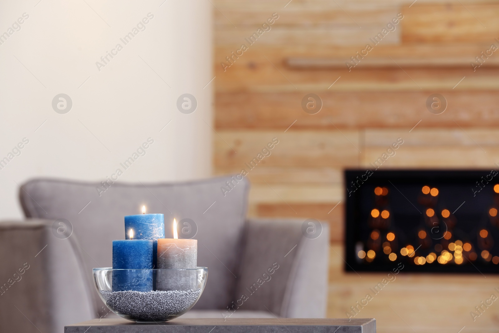 Photo of Bowl with burning candles on table in living room. Space for text