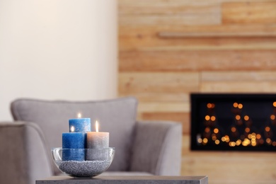 Bowl with burning candles on table in living room. Space for text