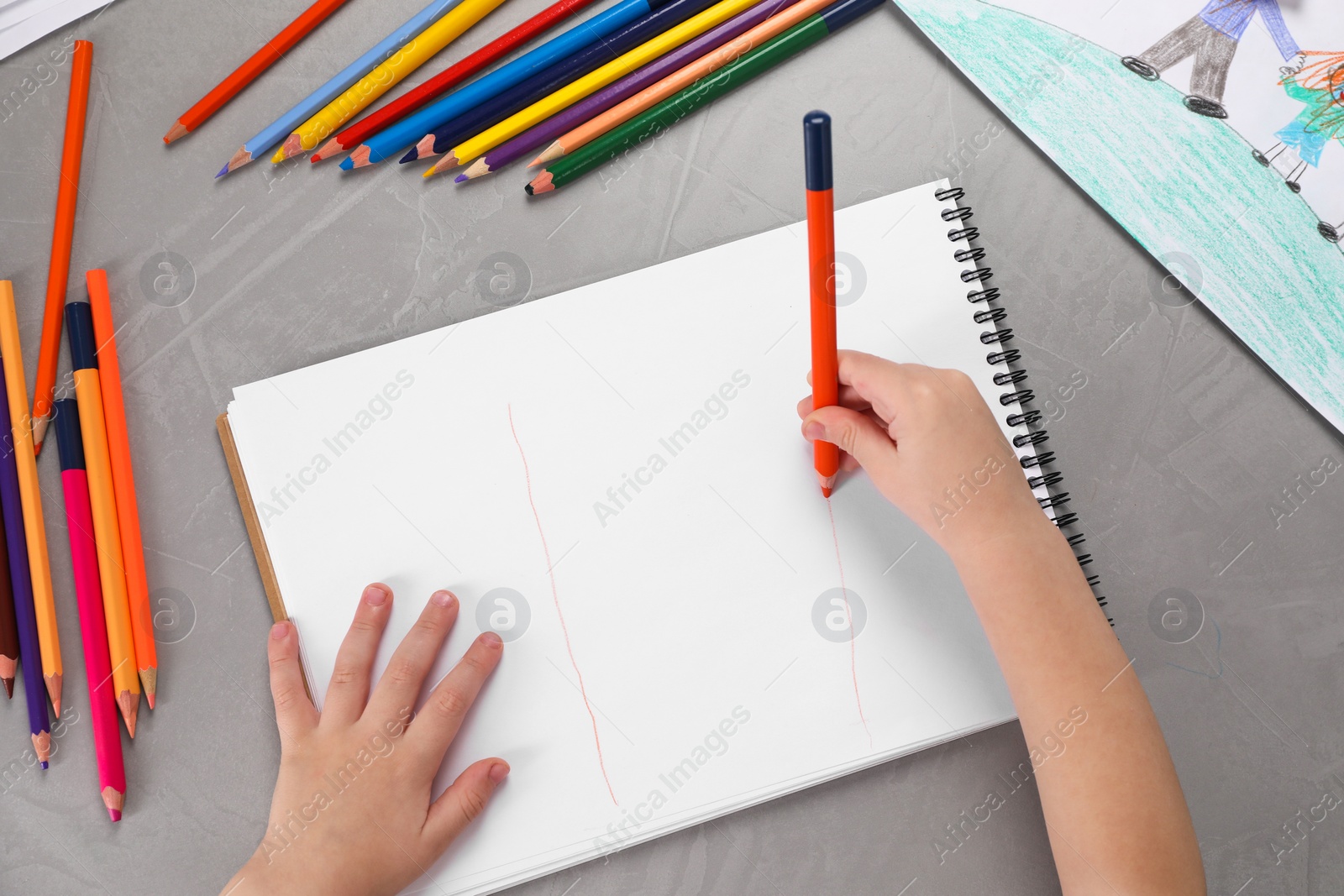 Photo of Little boy drawing with pencil at grey textured table, top view. Child`s art
