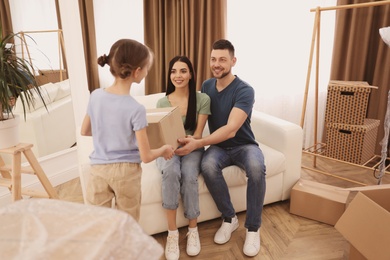 Photo of Daughter giving moving box to her parents in new house